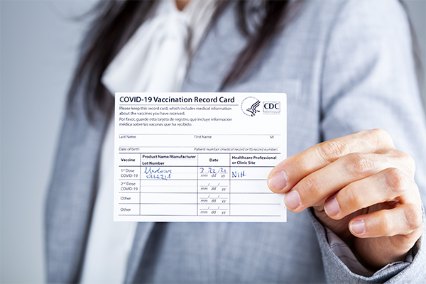 Woman in business suit holds COVID-19 Vaccine Card